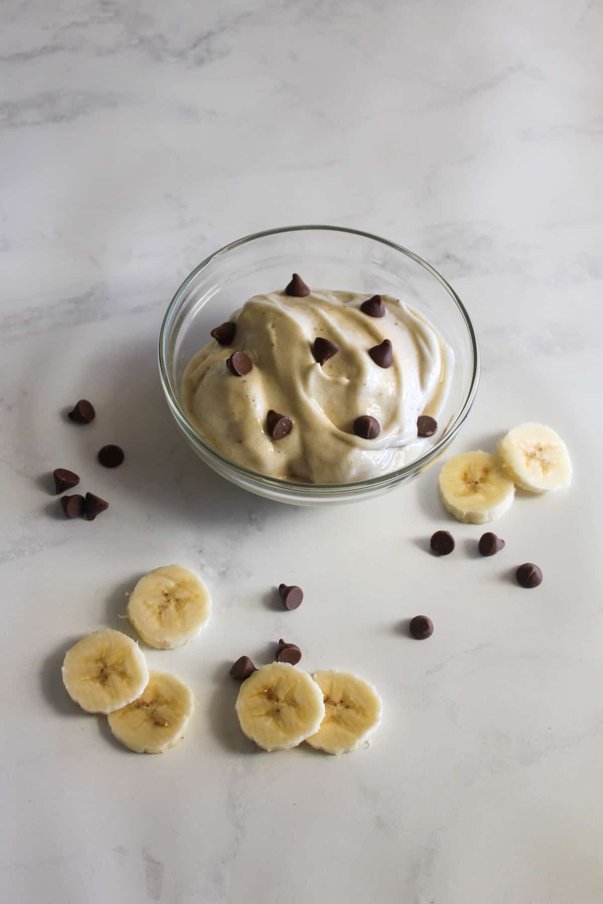 Banana ice cream in a glass bowl with choc chips and banana slices