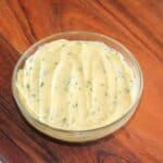 Garlic Butter in a glass bowl on a wooden chopping board