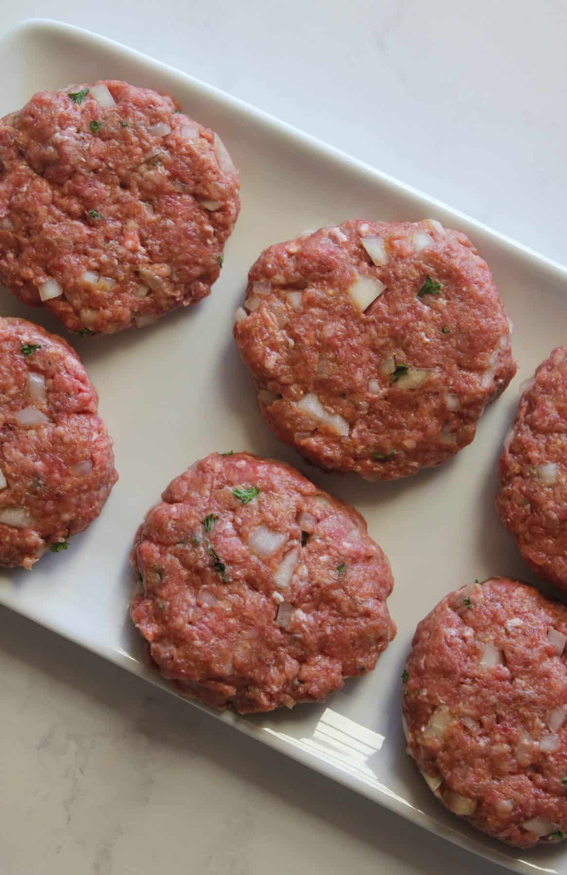 Raw rissoles on a white plate