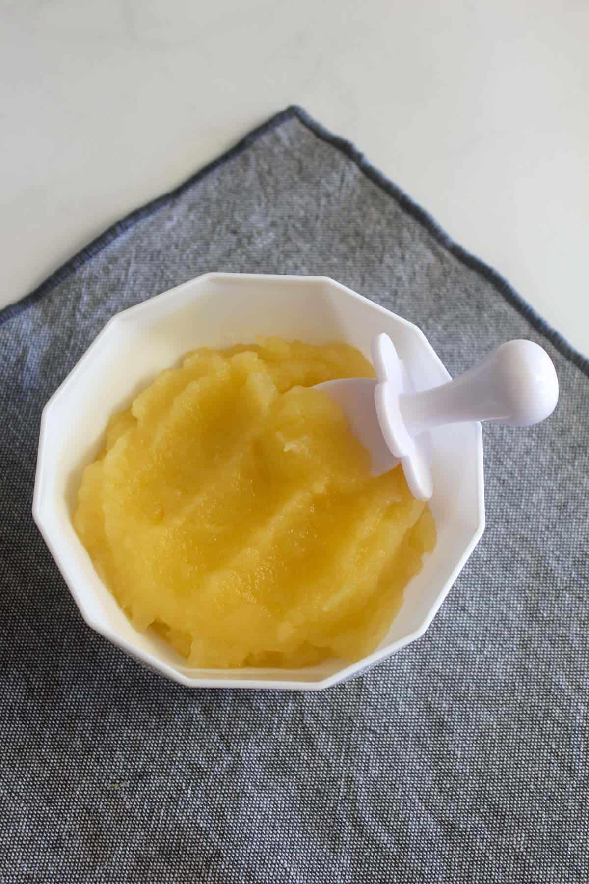 Puree in a white bowl and spoon and grey tea towel