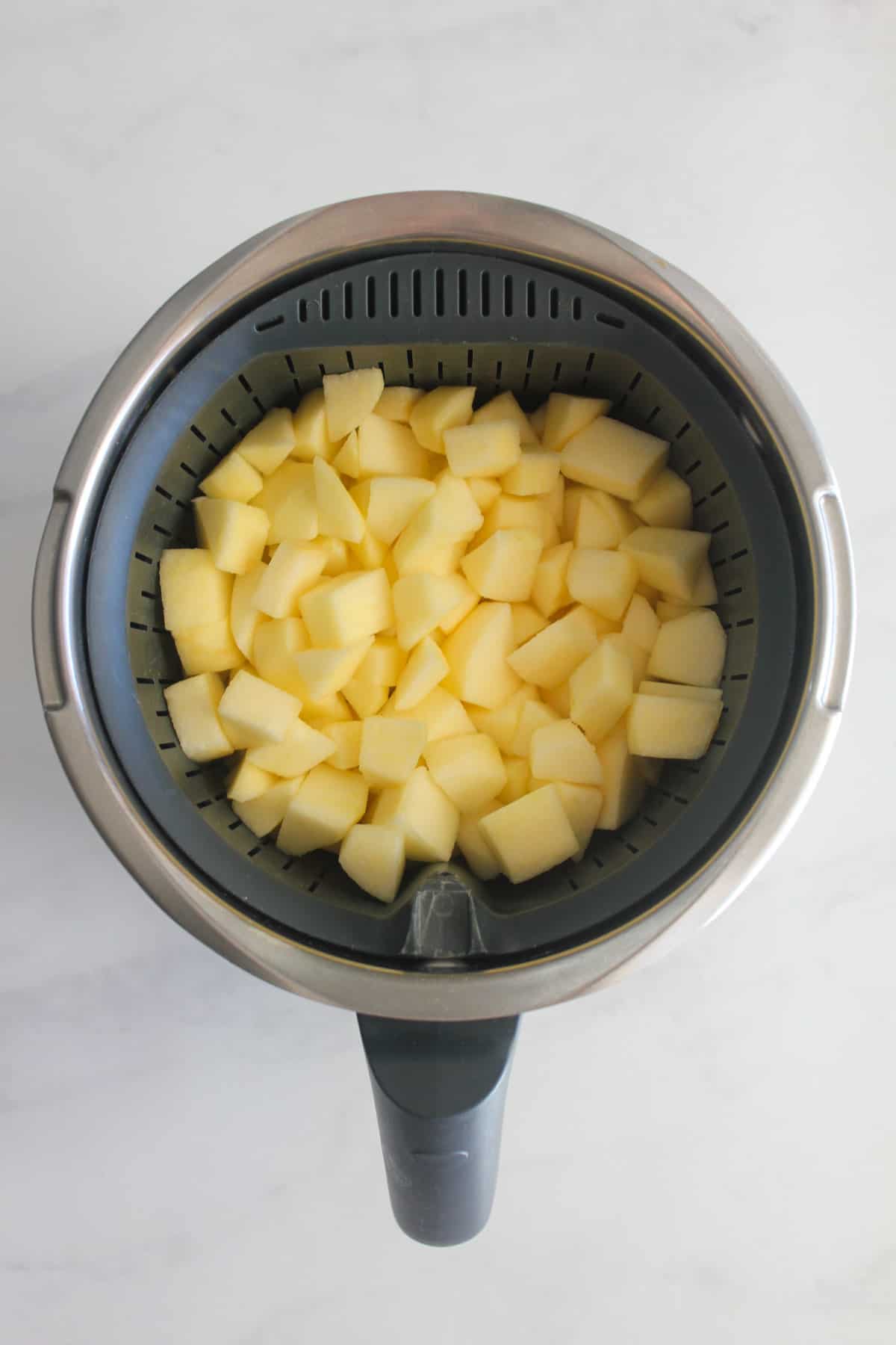 Diced apple in Thermomix with white background.