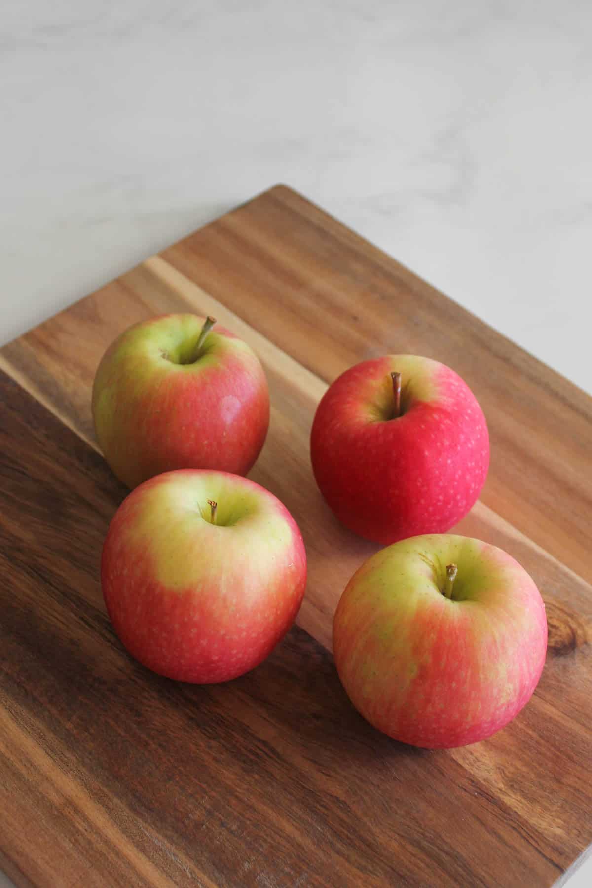 Pink lady apples on a chopping board on a white background