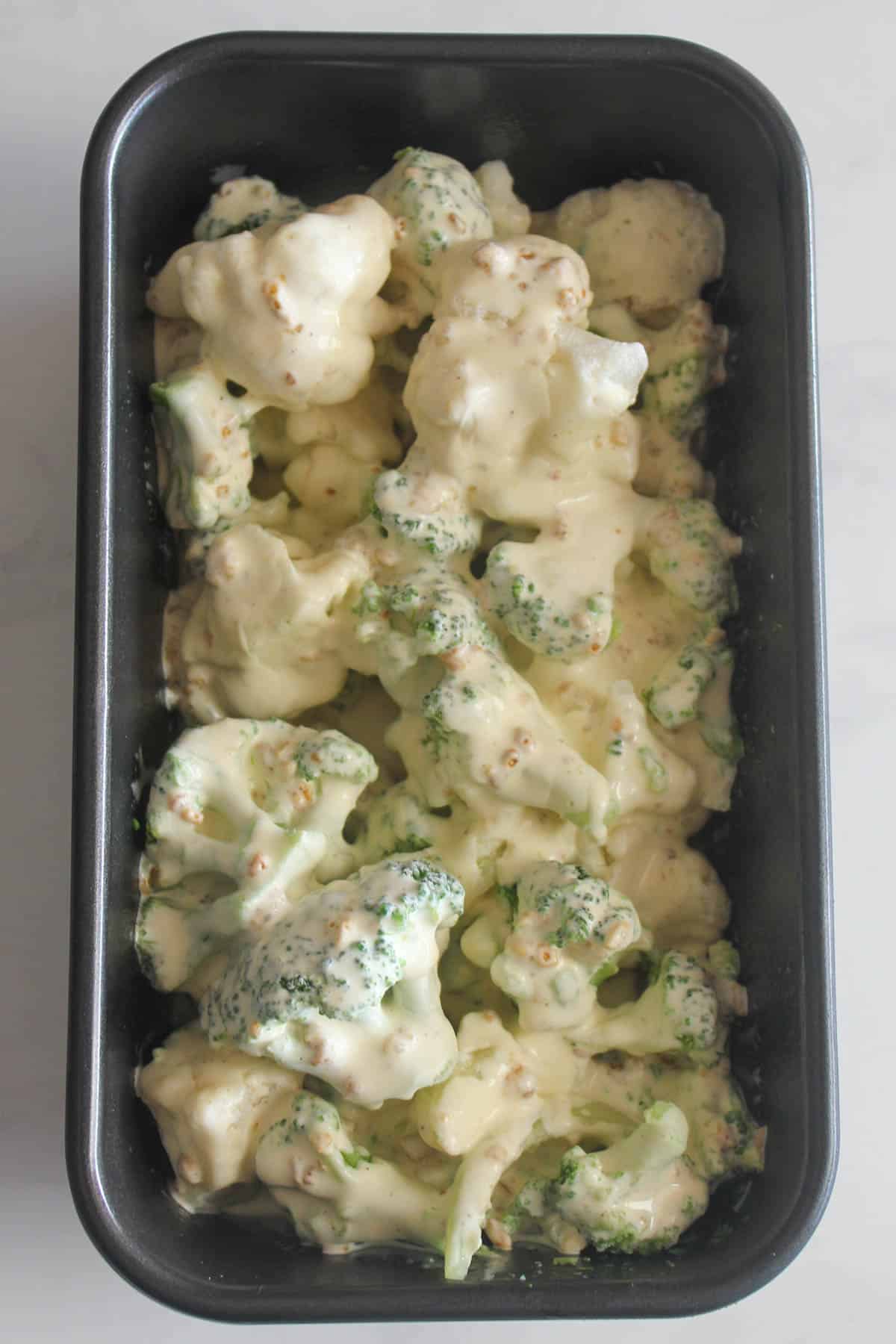 Broccoli and cauliflower in baking dish with cream over it.