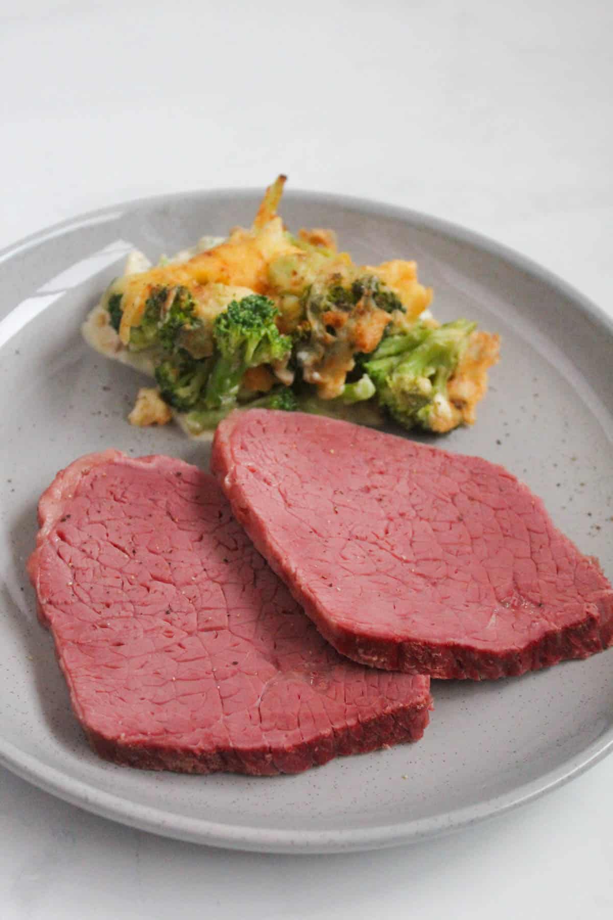 Sliced silverside with brocolli and cauliflower bake on a grey speckled plate