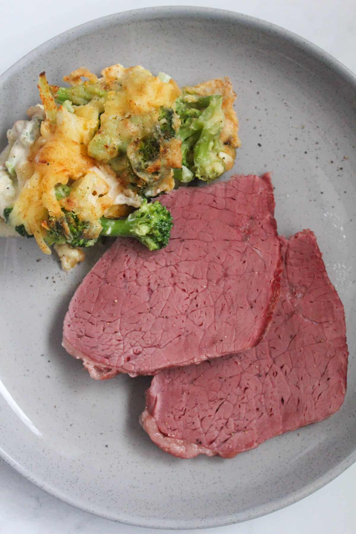 Sliced silverside with brocolli and cauliflower bake on a grey speckled plate