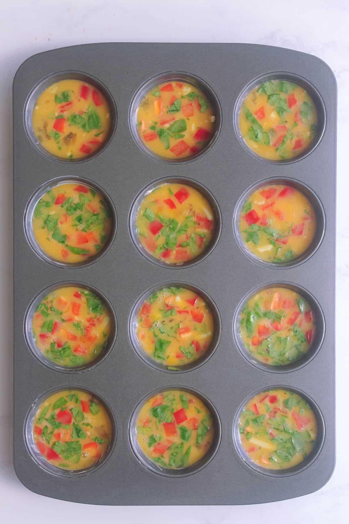 Egg muffin mixture poured into muffin tin ready to be cooked.