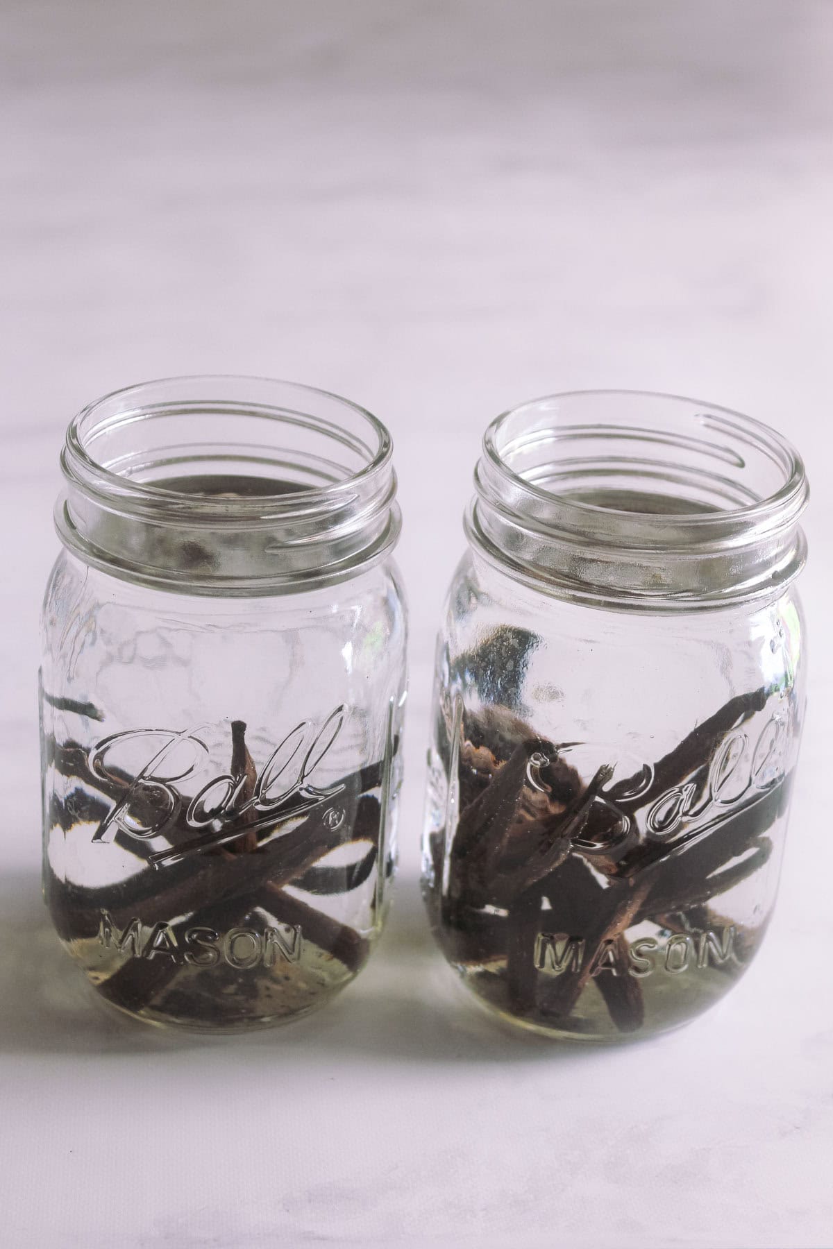 Cut up vanilla beans, place in glass jars with vodka poured over top, and infuse to make homemade vanilla extract.