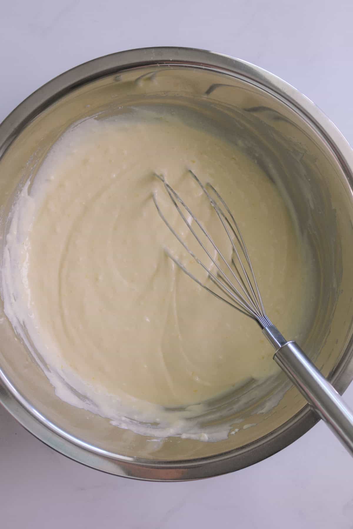 Pancake batter mixed in a stainless steel bowl with a whisk.