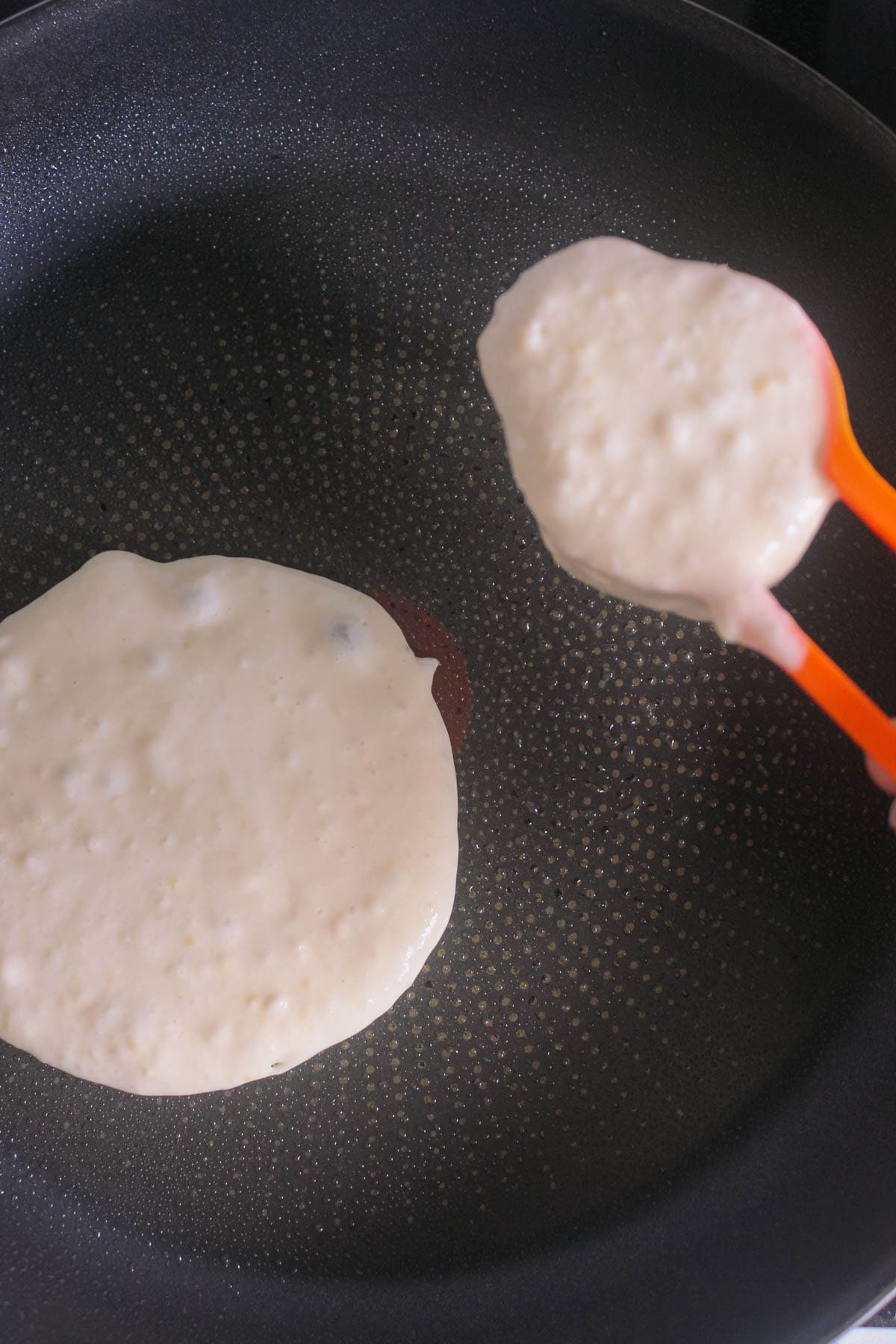 Pancake mixture in a measuring cup is being poured into a fry pan.