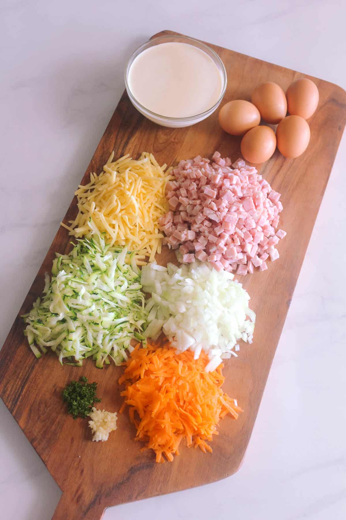 Quiche ingredients prepped on a wooden chopping board