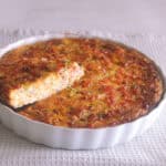 Crustless quiche in a quiche dish with a slice showing