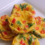 Baked egg muffins are placed together on top of each other on a white plate.