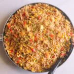 Fried rice in a frypan with a black spoon and white background