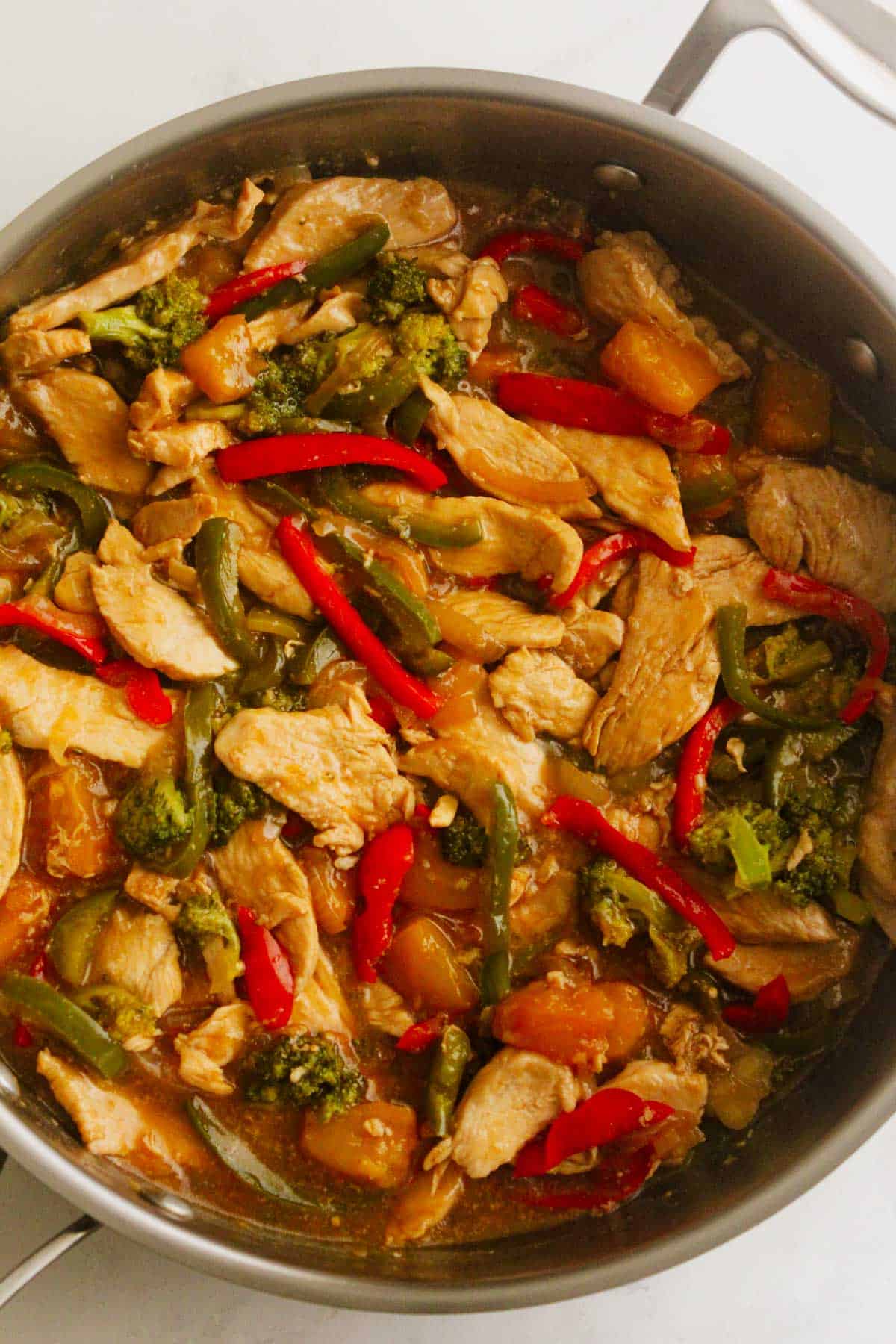 Honey soy chicken stir-fry in a frypan on a white background