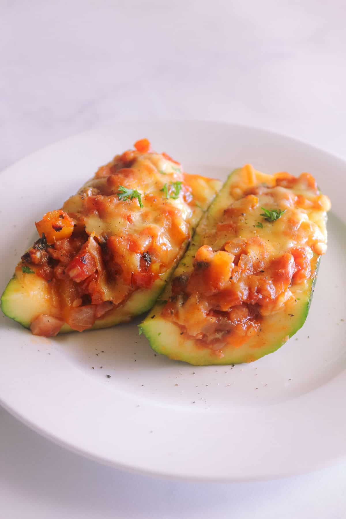 Zucchini boats cut in half on a white plate
